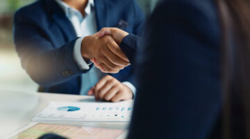 Business people, negotiation and handshake for deal, agreement or partnership in office. Shaking hands, closeup and hiring offer for recruitment, b2b collaboration or data analyst at table in meeting