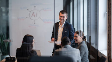 Diverse business team in a modern office during a meeting, discussing artificial intelligence strategy. Concept of AI innovation, teamwork, leadership, corporate planning, professional collaboration