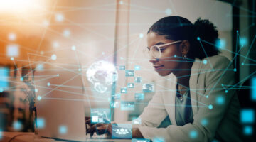 Business woman, AI and laptop with hologram, UX and networking for forex trading icon in office using virtual platform. Female using global technology for futuristic communication and innovation Leaders Debunk AI Myths: Elliott Broidy in Fast Company