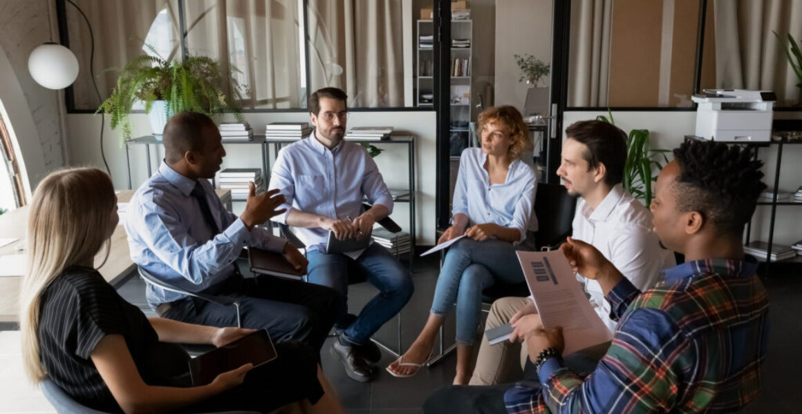 Multiethnic business team coworkers sitting in circle in office Ice Breaker Games for Company Retreats: Elliott Broidy in Fast Company