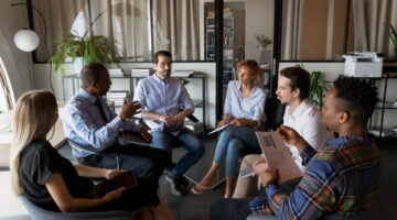Multiethnic business team coworkers sitting in circle in office Ice Breaker Games for Company Retreats: Elliott Broidy in Fast Company